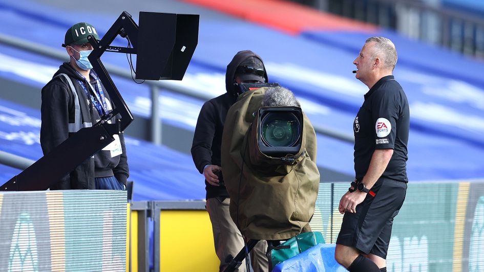 Referee Jonathan Moss looks at the pitchside monitor