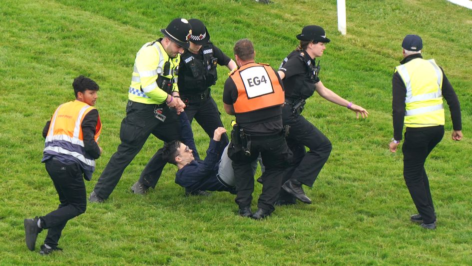 The protester is escorted from the track at Epsom