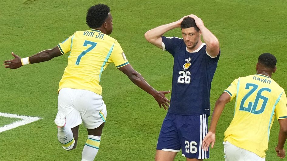 Brazil's Vinicius Junior (7) celebrates his goal with Rayan (26) as Scotland's Scott McKenna (26) reacts during the World Cup Group C soccer match between Scotland and Brazil