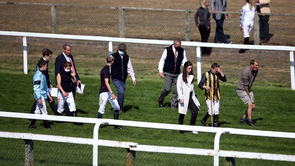 Officials and jockeys assess the track before the abandonment