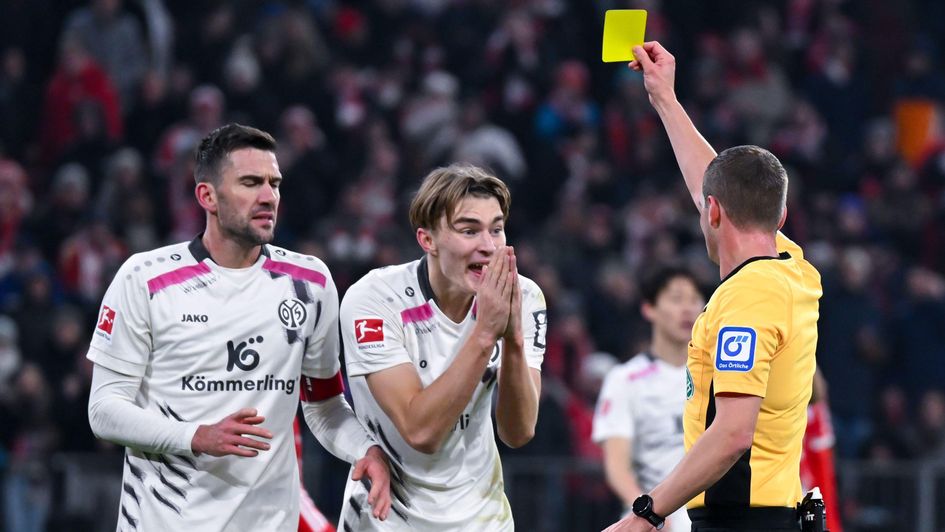 Mainz's Kacper Potulski is shown a yellow card by referee Robin Braun